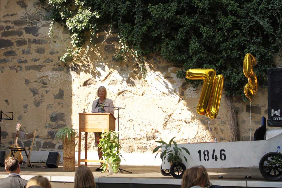 Dr. Christiane Prinzessin zu Solms-Hohensolms-Lich am Rednerpult auf der Bühne zur 175 Jahr Feier der ESTA, rechts eine Seifenkiste mit den verdrehten goldenen Ziffern 7, 1, 5