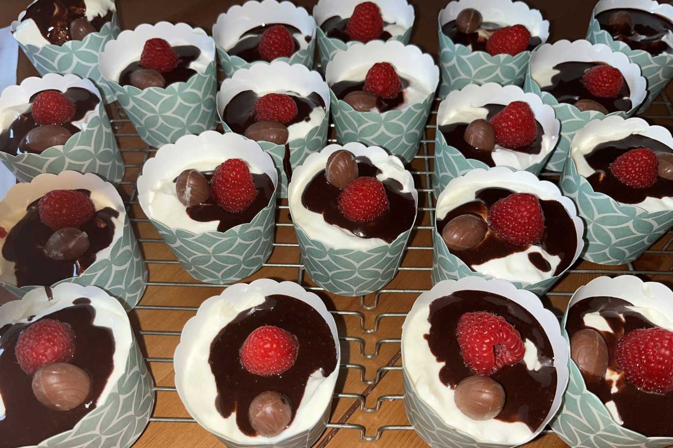 Mehrere selbstgemachte Muffins mit Schokoladensoße und Himbeeren