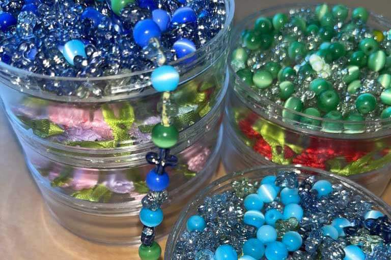Bunte Perlen in hellblau, dunkelblau und grün in Gläsern