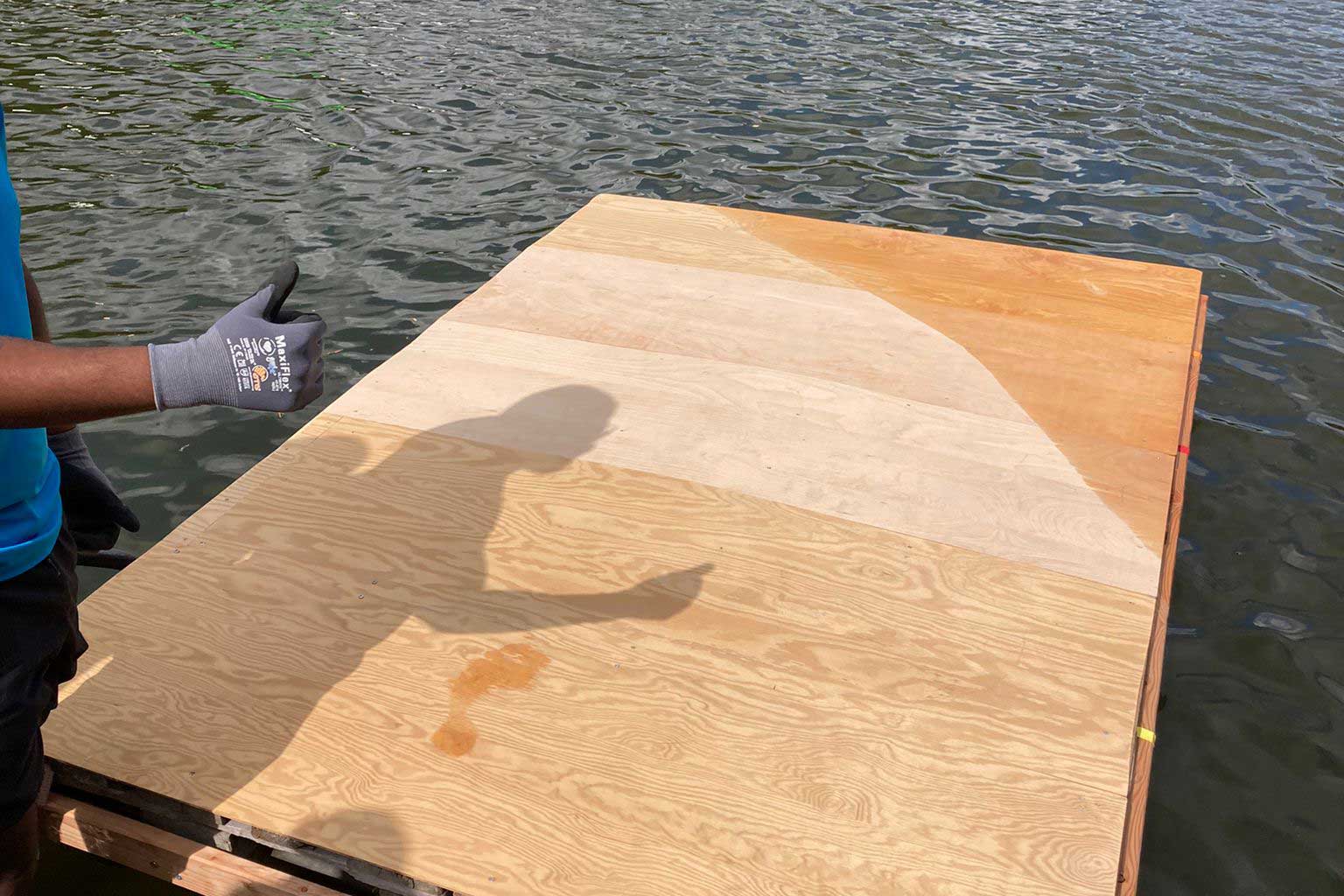 Massives Holzfloss am Seeufer, ein Mann mit Arbeitshandschuh zeigt Daumen hoch