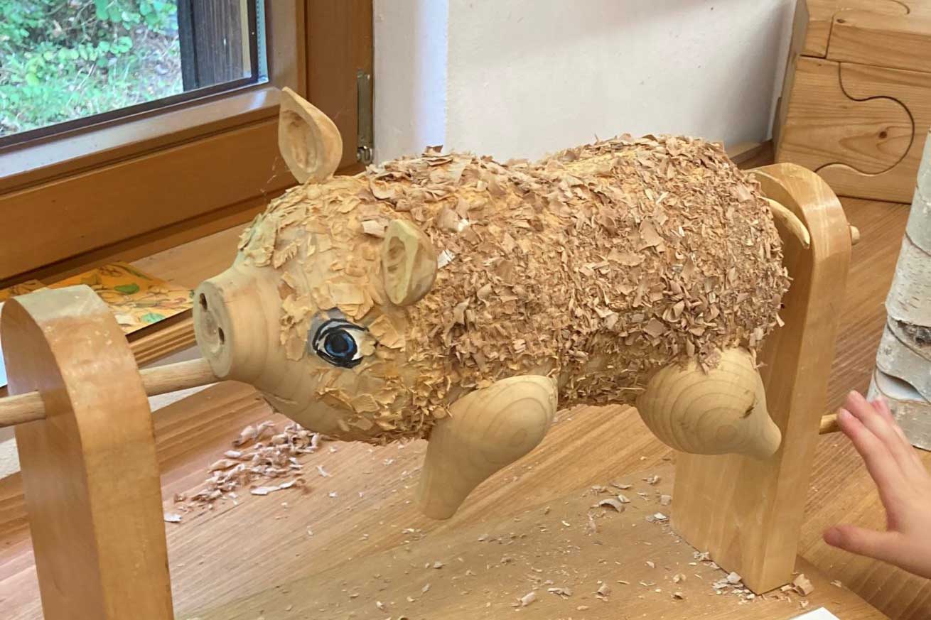 Ein aufgespießtes Holz-Ferkel mit blauen Augen und Spänen auf dem Rücken