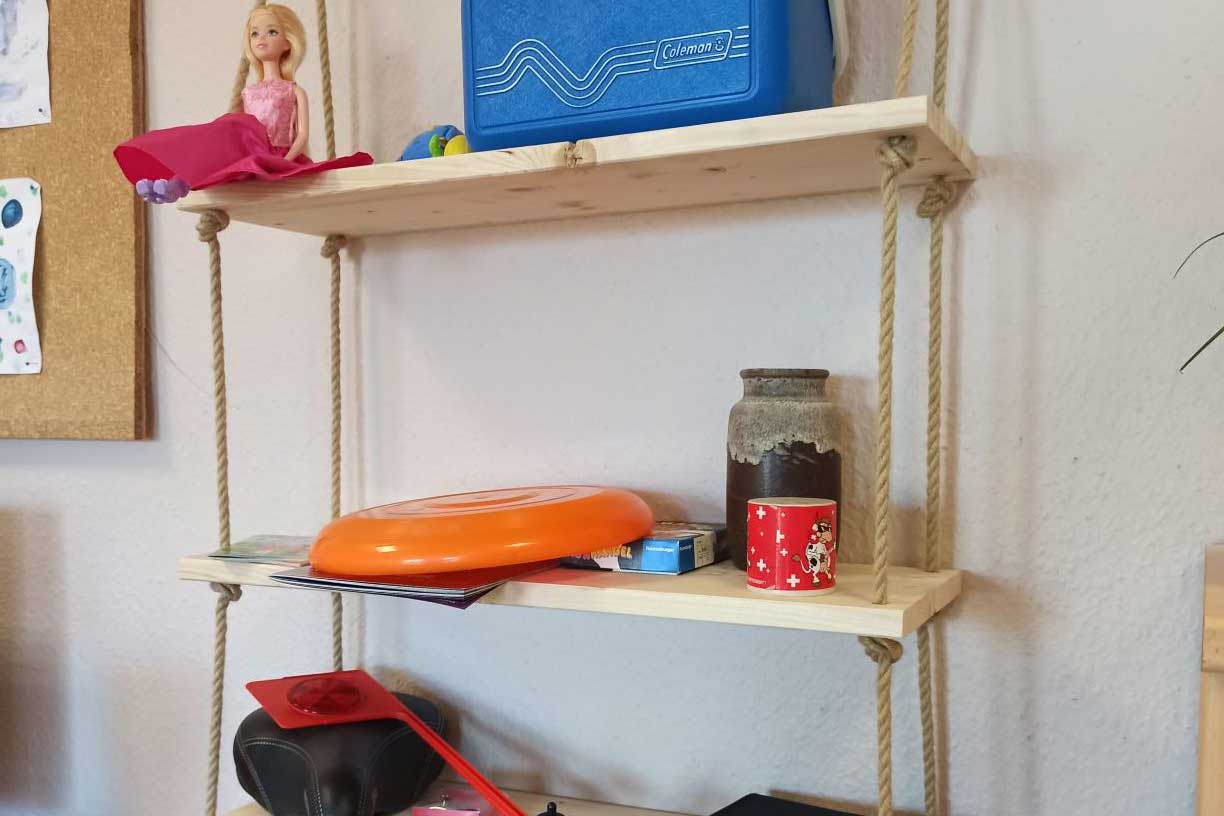 Regal mit verschiedenen Gegenständen, wie eine Barbiepuppe, Frisbeescheibe, Vase, Fahrradsattel und -abstandhalter