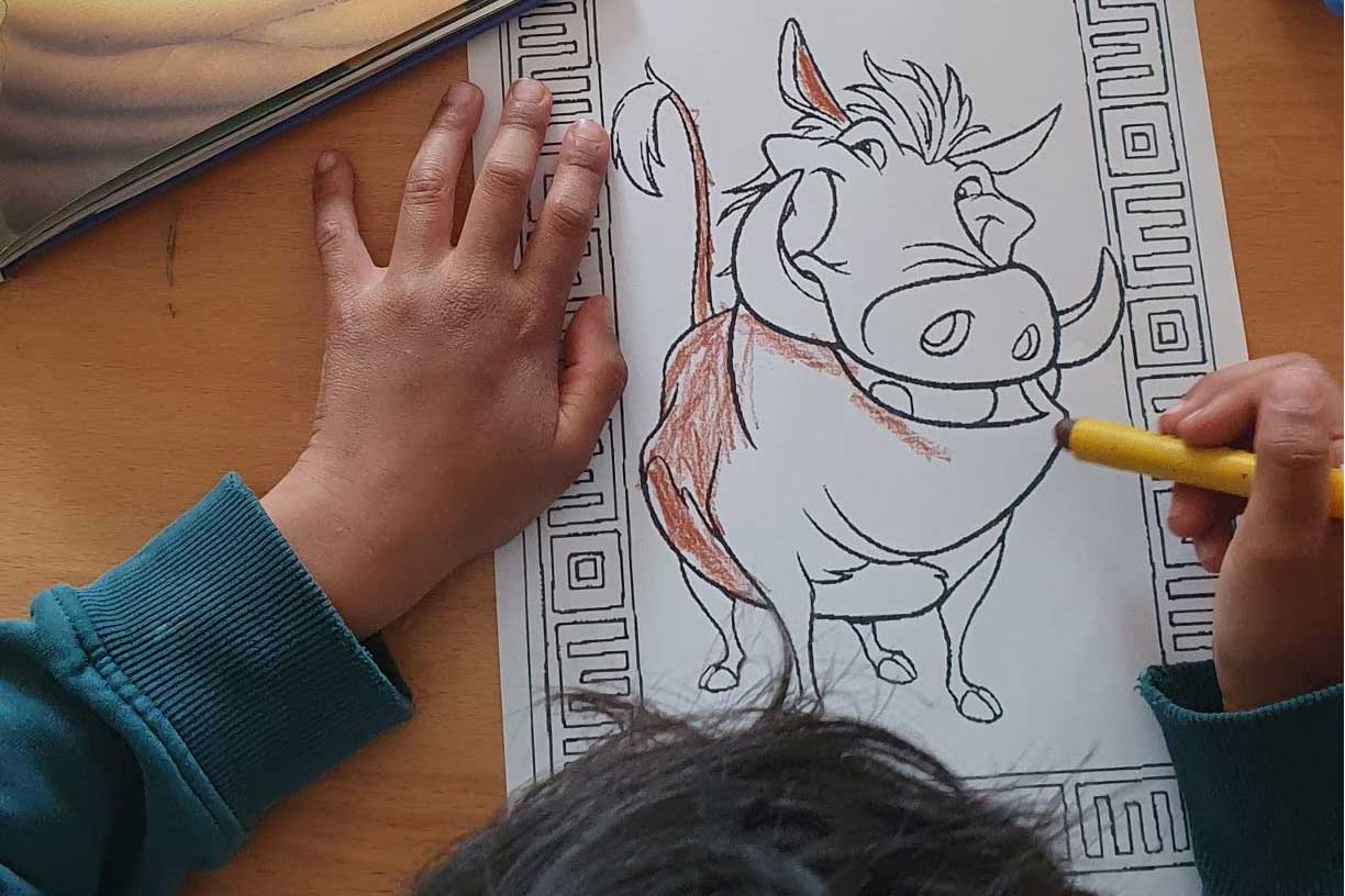 Ein Kind malt eine Zeichnung des Warzenschweins aus König der Löwen aus