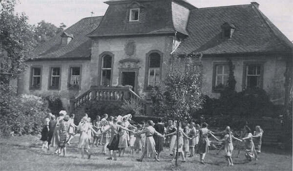 Mädchen tanzen 1877 im Kreis vor dem Haus des Mädchenerziehungsheims