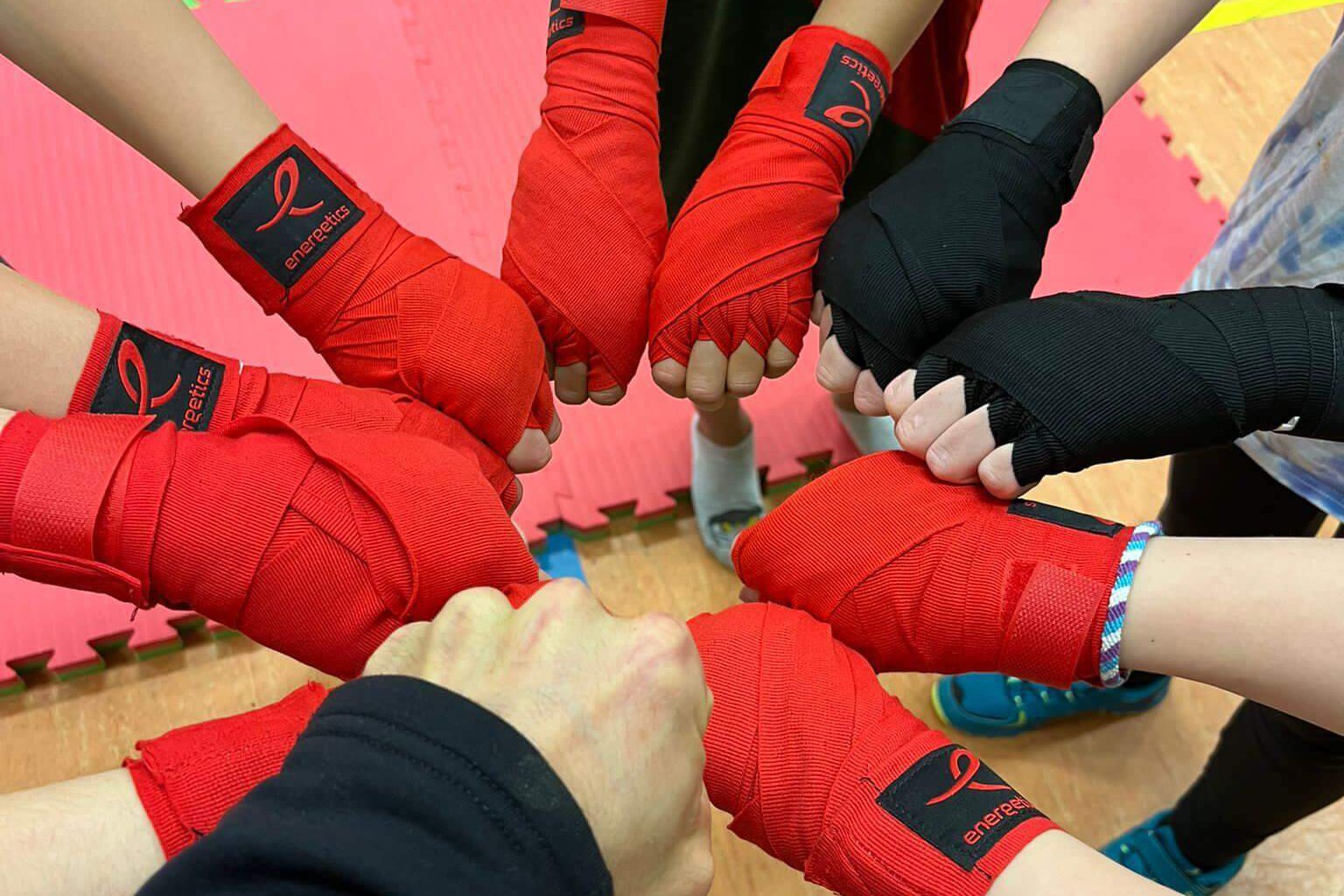 Alle Kinder tragen Kickboxhandschuhe und legen alle Hände zusammen.