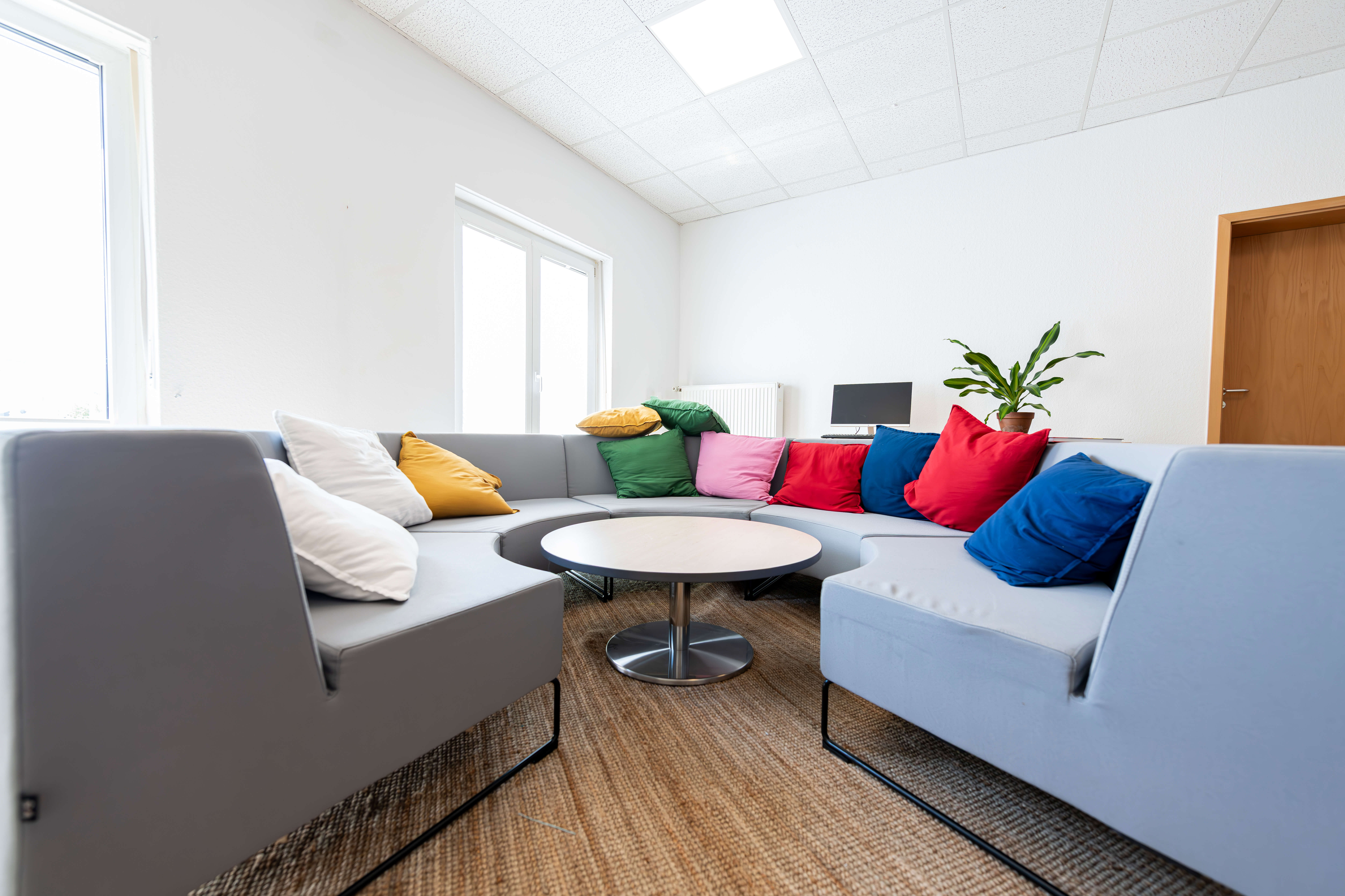 Graues halbrundes Sofa mit bunten Kissen